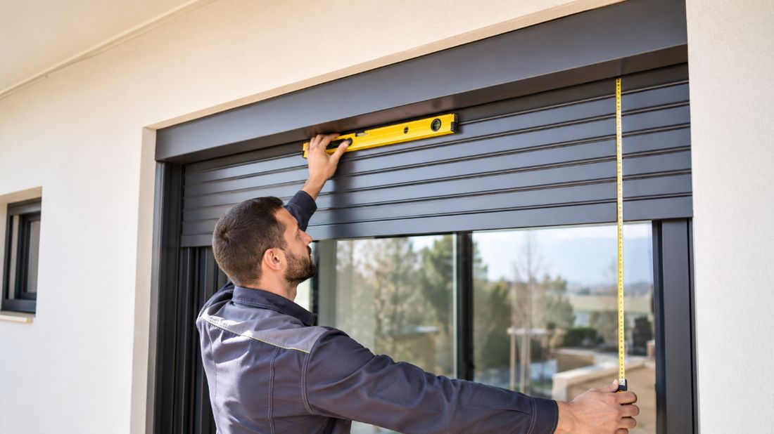 Técnico midiendo una ventana con nivel y flexómetro para una persiana a medida